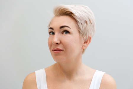 Portrait of an adult smiling beautiful woman with blonde hair. gray background. The concept of...