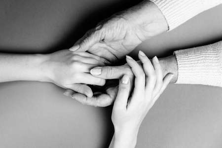 Mother and daughter holding hands. close-up. flat lay. Black and white colors. The concept of caring for the elderly.の写真素材