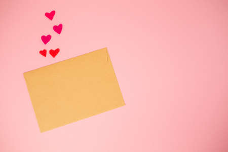An envelope made of kraft paper with hearts cut out of felt. pink background. copyspace. Mock up....