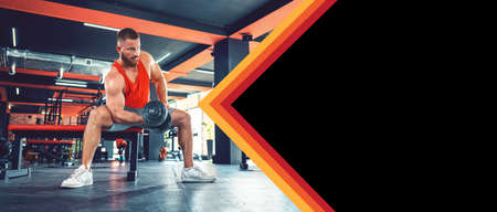Banner of fitness with mock up. A young bearded athletic man with effort trains with dumbbells in the gym. copyspace. The concept of fitness and wellness.の写真素材