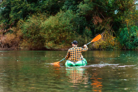 watersport. Man in shirt and cap kayaking at the river. back view. The concept of the World Tourism...