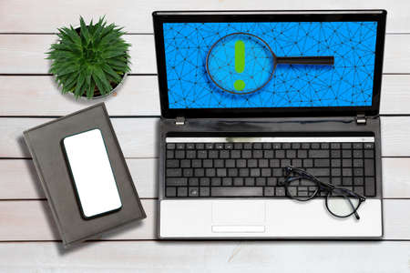 Laptop with notepad, cellphone and glasses on the wooden background. flat lay. Internet searching. Concept of VPN and online security.の写真素材