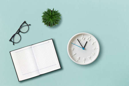 office template. Eyeglasses, notepad, clock and succulent on the mint color background. flat lay. concept of education.の写真素材