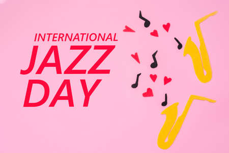 A cutted out of felt saxophones from which hearts and melodies flew out, on a pink background. flat lay. International Jazz Day.の写真素材