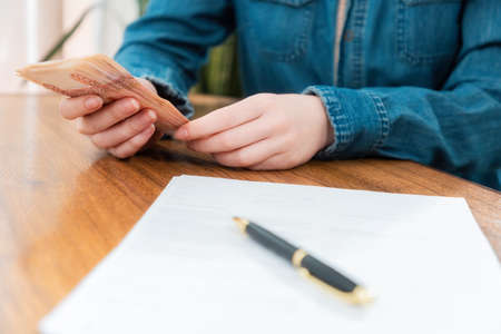 Close up of key with keychain lies on the table. Defocused person's hands counting money at the background. Concept of leasing and mortgage.の写真素材
