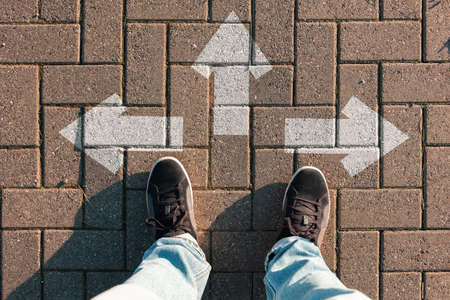 Person stands on the road, choosing the direction of the path. Arrows on the ground. Top view, fit...