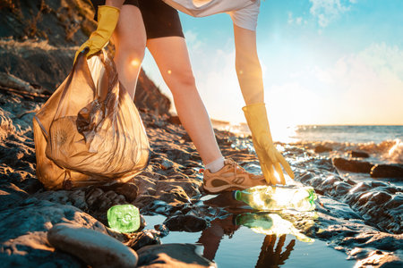 Cleaning the coastal zone. An pick up activists up a plastic bottle on the beach. close up of hands....
