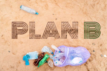 Trash bag with plastic bottles on a sandy beach. Text PLAN B on a sand. top view. flat lay. The...