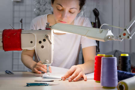 a sewing machine for which the dressmaker works in soft focus.の写真素材