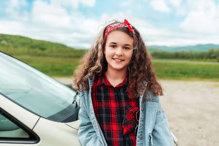 Travel and holidays. Portrait of pretty smiling teen girl standing by a vehicle. The concept of...