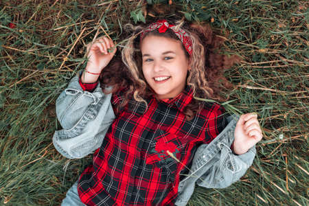 Portrait of happy Caucasian teen girl lying on the grass and looking at the sky. view from above. The concept of carefree, freedom and psychology.の写真素材