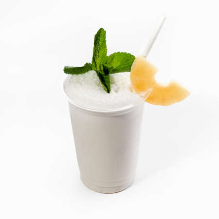 A cool delicious Pina colada decorated with mint and a slice of pineapple. Close up, on a white...