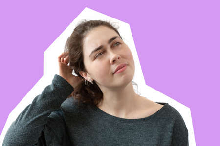 The young woman thinks, ponders the idea, thinks about something. Lilac background. copyspace.の写真素材