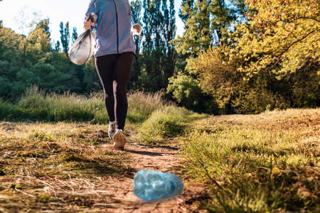 Person in sportswear jogging at the park and holding a bag of garbage. bottom view. The concept of...