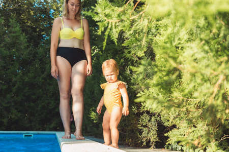 summer holidays. Caucasian plus sized mother and her little daughter going to swim at the pool.の写真素材