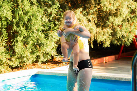 A mother plays with her little daughter in the pool. summertime.