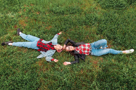 Happy Caucasian mother and daughter are lying on their backs on the grass and looking at the sky....
