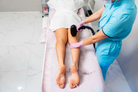 Cosmetologist does a laser hair removal procedure on woman's legs. close up of feet. top view. The concept of epilation and professional care in beauty salon.の写真素材