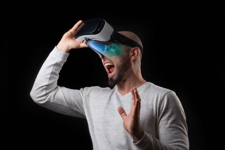 Portrait of young had shocked screaming man removing VR glasses and offset from virtual reality....