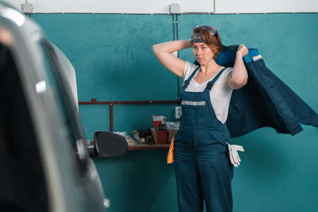 A young female mechanic wear on a work jacket. The concept of women's work in men's professions and...