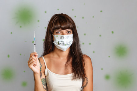 medicine and seasonal viral diseases. A woman in a medical mask holds a syringe in her hand. Green virus at air.の写真素材