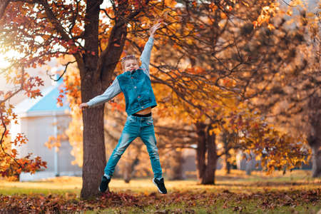 A happy boy jumping in the autumn park. The concept of school holidays.の写真素材