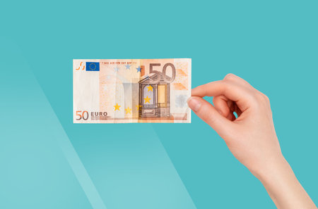 Collage of finance. A woman's hand holds a paper euro bill. Turquoise background. The concept of...