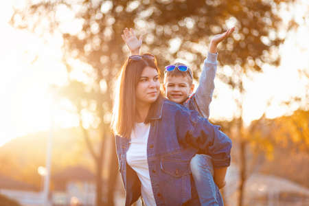 Portrait of young mother and smiling son play in an autumn park. The concept of a happy childhood.の写真素材