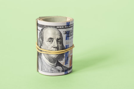 Bribe. A bundle of dollar bills wrapped in a roll close-up on a green background. The concept of investment, financing and savings.の写真素材