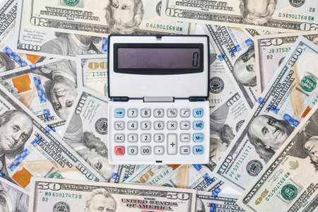 finance and mortgage. Calculator is located on scattered new dollar bills, close-up. flat lay. The concept of accounting, business and taxes.の写真素材