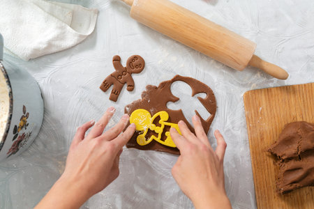 Female's hands cut out cookies from the dough in the form of ginger man. top view. Close-up of hands. The concept of home cooking and Christmas.の写真素材