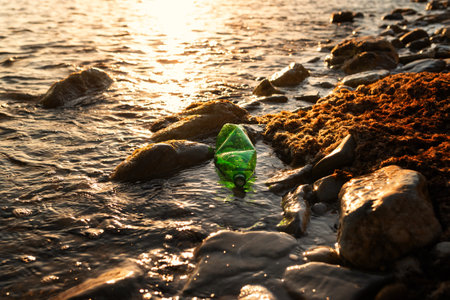 Pollution of seas and rivers. Ecosystem conservation. A green plastic bottle is lying in the water...