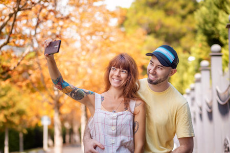 Portrait of young couple posing at the street and taking selfie at the smartphone. Happy caucasian...