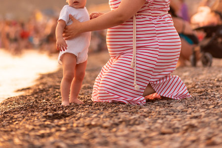 motherhood and pregnancy. Young caucasian pregnant woman walking with child at the beach. close up. copyspace. low angle view. concept of maternity and parenthood.の写真素材