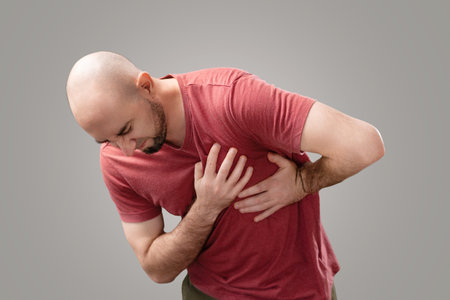 A bearded bald man grabs his chest with his hand, experiencing severe pain. lung disease. The...