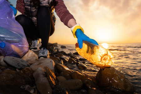 A female volunteer collects garbage on the ocean. Cleaning of the coastal zone and preservation of...