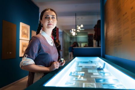 Cultural education and excursion. Side view of caucasian pretty young woman contemplates exhibition. electric blue light. Concept of exhibition in gallery.の写真素材