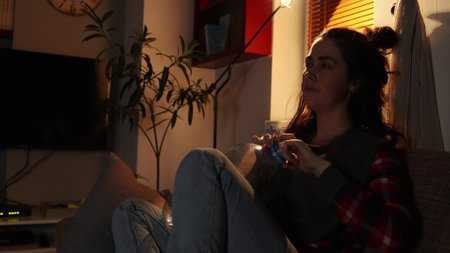 Caucasian tired woman sitting on sofa drinks water from large bottle that is empty. home evening. Sickness and thirst.の写真素材