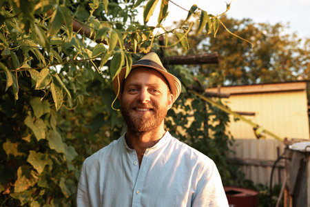 organic gardening. Portrait of bearded smiling caucasian farmer posing at garden. The concept of harvesting and farming.の写真素材