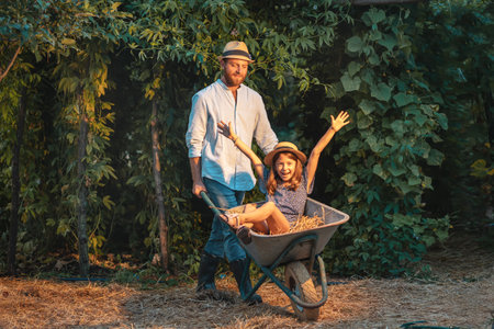 Caucasian father in a straw hat pushing a cart with a cheerful little daughter. Family weekends...