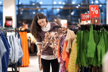 shopping and consumerism. Beautiful young Caucasian woman choosing and trying new clothes. Concept...