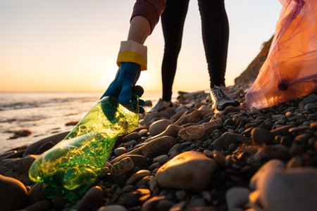 Conservation of ecology and garbage collection for recycling. A volunteer collects plastic bottles by the sea. Concept of coastal cleanup and global environmental pollution.の写真素材