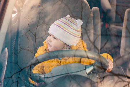 Cute little girl playing with steering wheel in car. view through windshield. The concept of learn driving and traffic rules.の写真素材