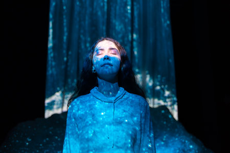 Schizophrenia and enlightenment. Portrait of young woman with closed eyes posing in blue light from illusion of waterfall. Concept of psychology, mental health and dreaming.の写真素材