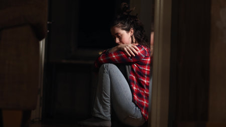 depression and mental disorder. Young Caucasian woman sits down on floor in despair and suffering crying. side view. Concept of psychological health and trouble.の写真素材