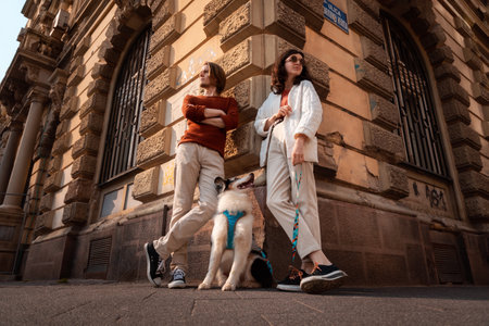 Bottom view of young Caucasian couple with pet poses against background of build. Training purebreed aussie dog.の写真素材