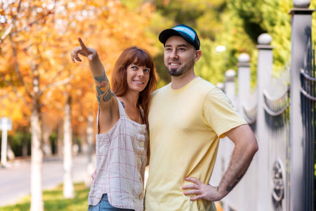 Travel and adventure in the city. Happy young bearded man and a young woman with tattoos hug on the street and look into the distance. The concept of relationship psychology.の写真素材