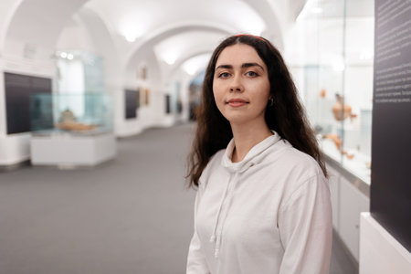 Portrait of young smiling caucasian woman posing in museum. light hall background. Concept of...