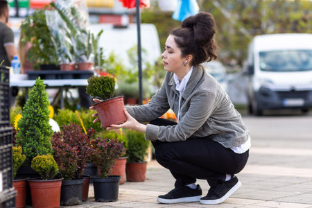 Side view of young woman choosing flower pot at spring festival. gardening and farming.の写真素材