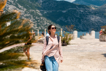 Smiling young woman walking through old stone city. Mountains in the background. Summer holidays and...